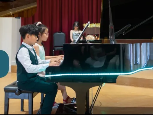 Two students playing the grand piano together at a Horizon recital